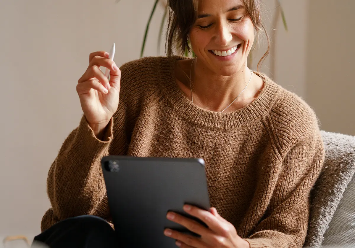 Kobieta w salonie korzysta z tabletu i rysika, przeglądając porównanie modeli.