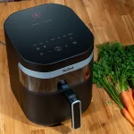 Tefal Easy Fry Infrared EY8328 - frytkownica beztłuszczowa z technologią podczerwieni na drewnianym blacie obok świeżych marchewek