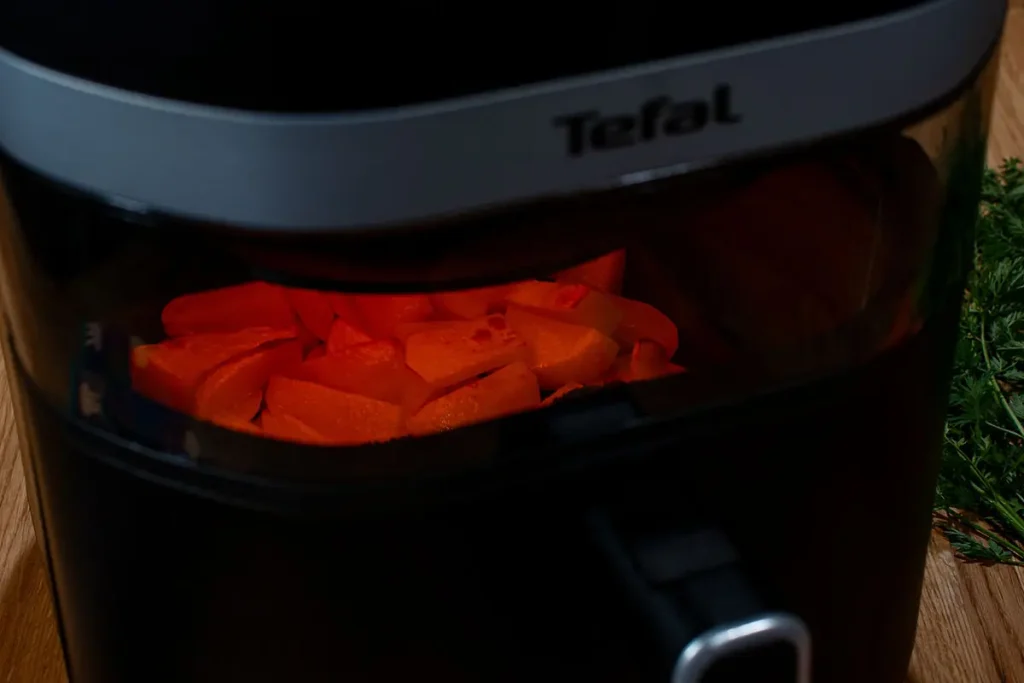 Ziemniaczki pieczone w Tefal Easy Fry Infrared EY8328 oświetlone czerwonym blaskiem grzałki podczerwieni InfraHeat widocznym przez okienko