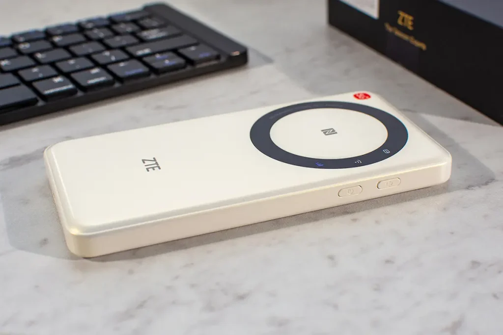 Boczny widok mobilnego routera 5G ZTE U30 Air na biurku – widać obudowę, przyciski na boku i okrągły panel z NFC (recenzja).