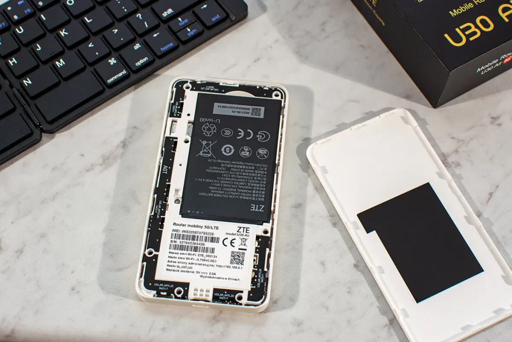 ZTE U30 Air po zdjęciu klapki – widoczna bateria i wnętrze obudowy mobilnego routera 5G, obok leży tylna pokrywa (recenzja).