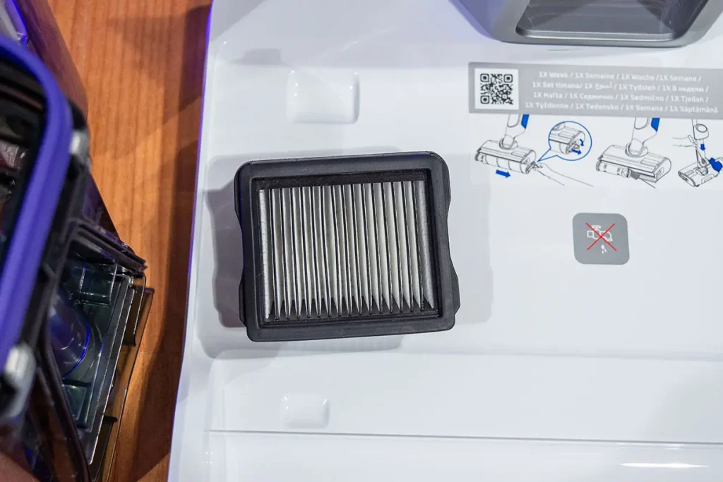 Filtr EPA odkurzacza myjącego Tefal X-Clean 10 GF7540 wyjęty i leżący na białej stacji dokującej obok instrukcji konserwacji z zalecaną częstotliwością czyszczenia raz w tygodniu