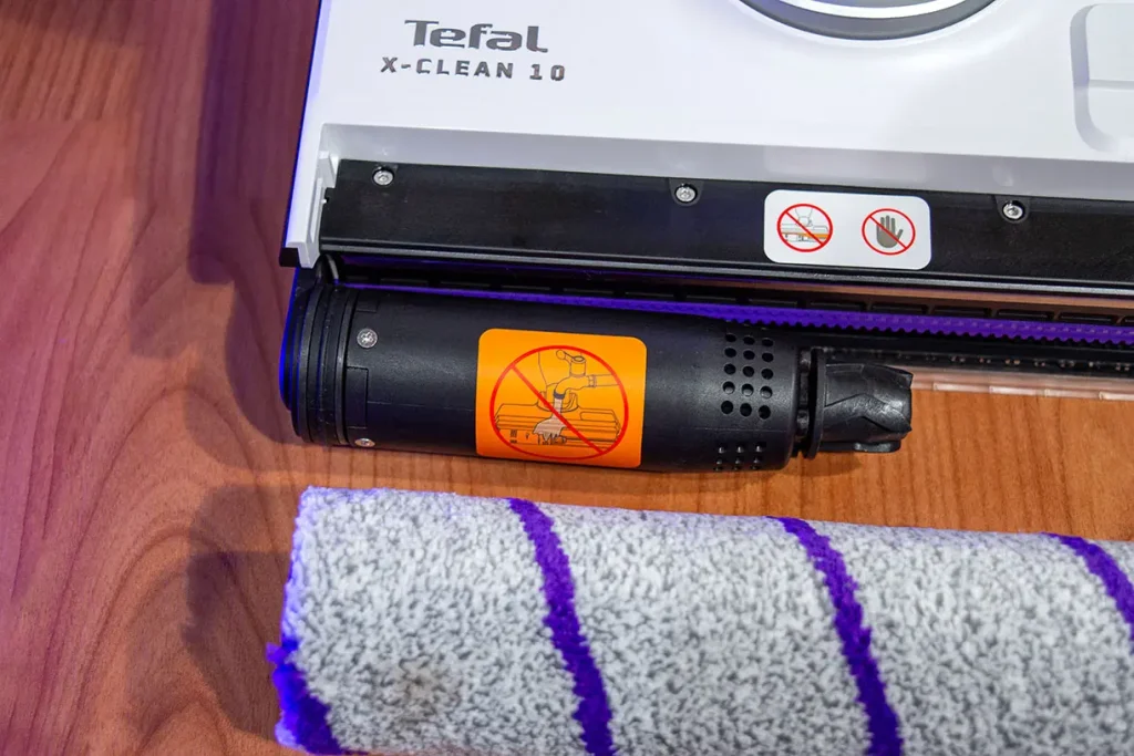 Silnik bezpośredni napędzający wałek odkurzacza myjącego Tefal X-Clean 10 GF7540 z pomarańczową naklejką ostrzegawczą zakazu mycia pod kranem