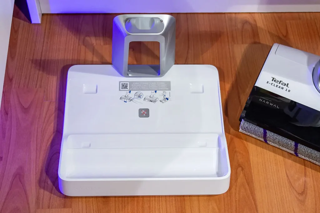 Pusta stacja dokująca odkurzacza myjącego Tefal X-Clean 10 GF7540 z widocznym srebrnym uchwytem i instrukcją wymiany wałka - widok z góry