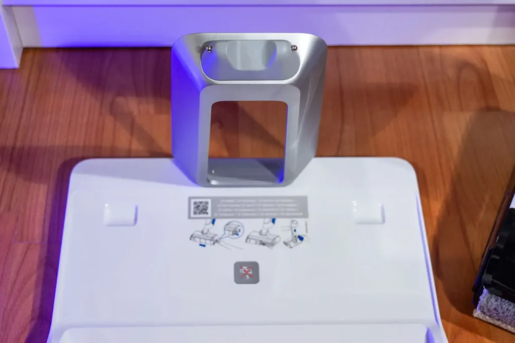 Stacja dokująca odkurzacza myjącego Tefal X-Clean 10 GF7540 - zbliżenie na srebrny uchwyt z stykami ładowania i instrukcją wymiany wałka